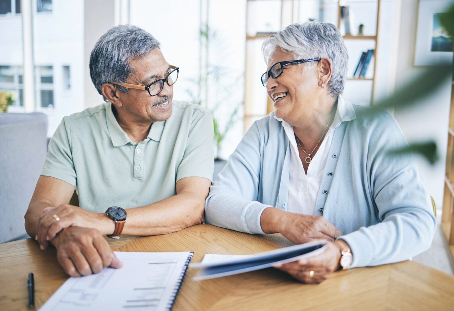 Older couple smiling while reviewing documents together.