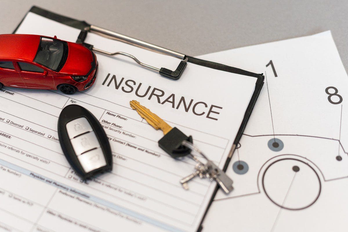 Car insurance documents with keys and toy.