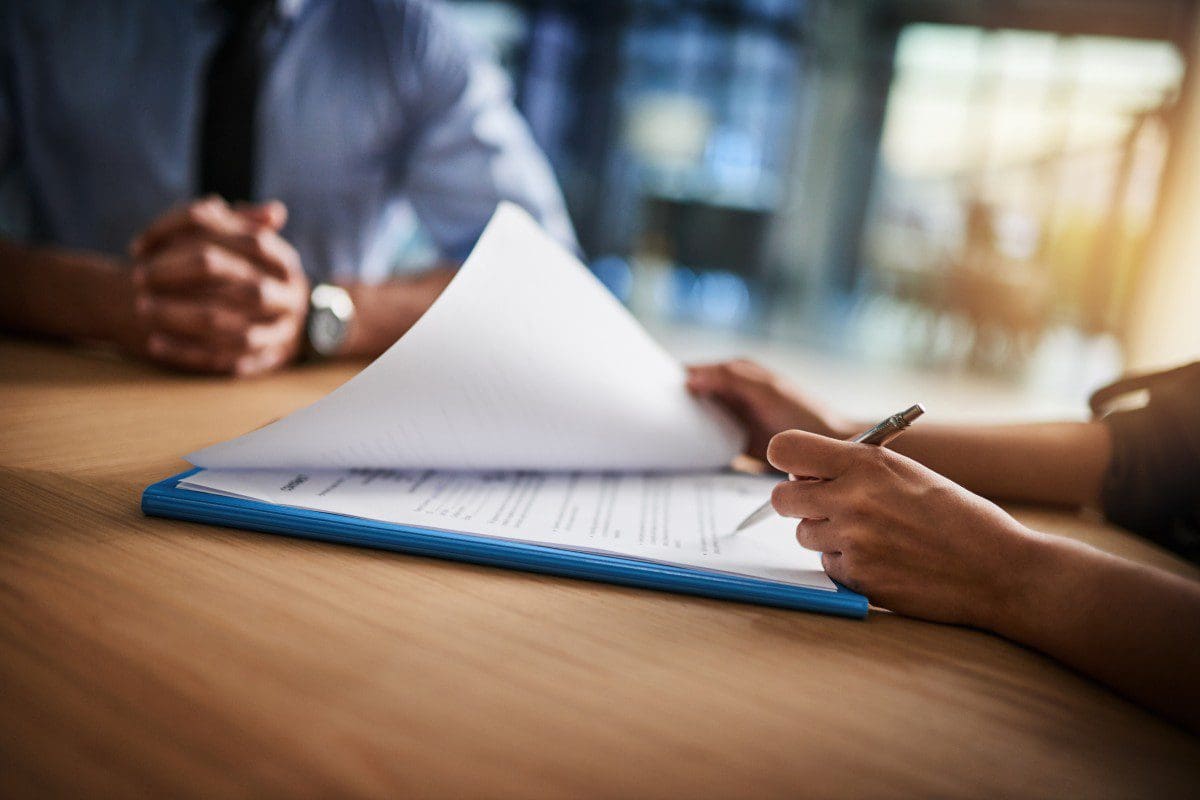Signing documents at a wooden table.
