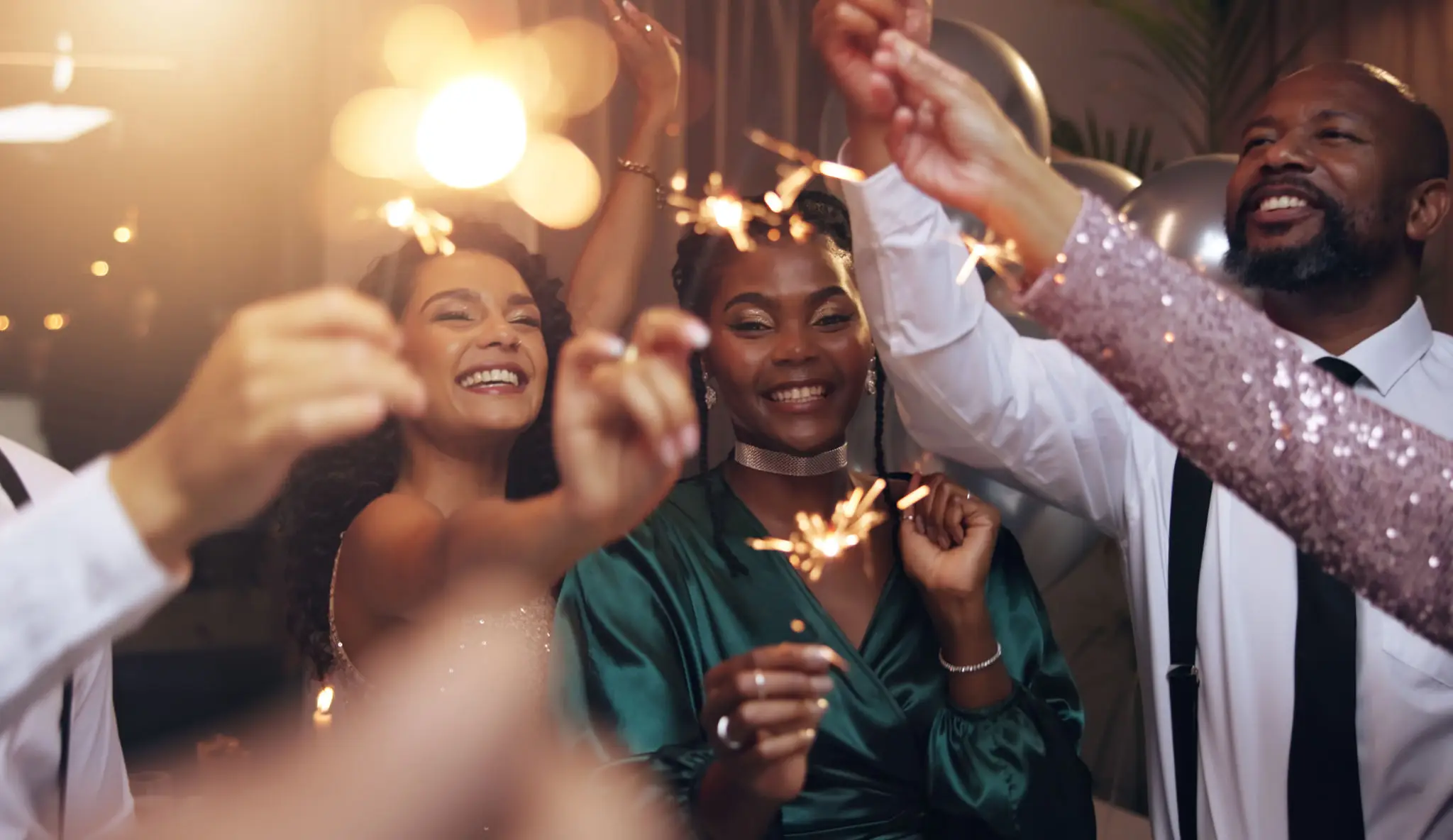 Group of friends joyfully holding sparklers at a celebration.