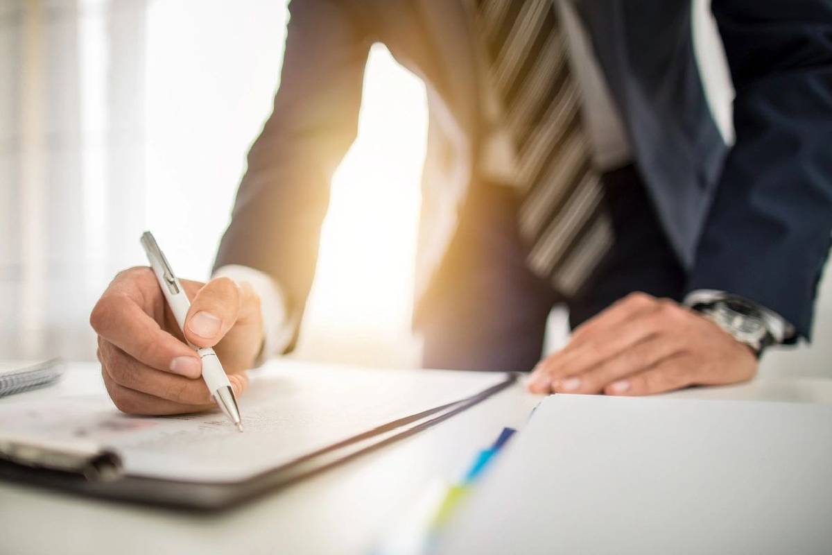 Businessperson signing documents at a desk.