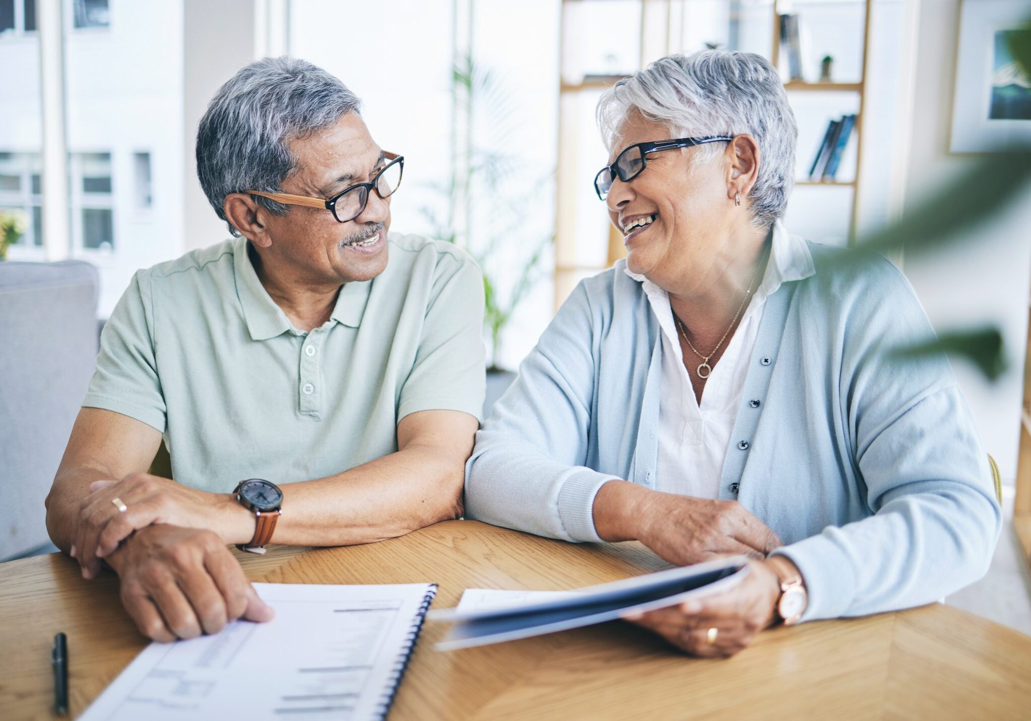 Older couple smiling while reviewing documents together.