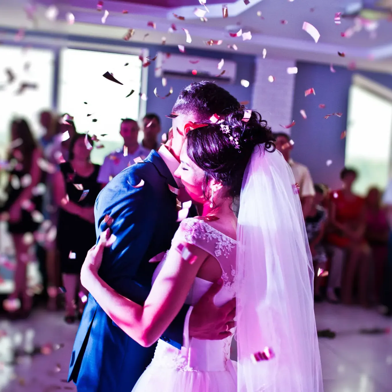 A bride and groom share a joyful first dance amidst falling confetti.